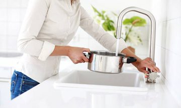Femme qui remplit une casserole avec de l'eau osmosée pour cuisiner